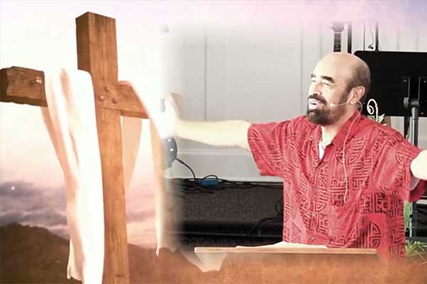 Pastor Kilborn preaching beside a wooden cross at The Church at Koloa on Kauai.